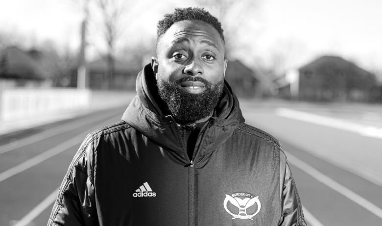 Image of a man wearing an Adidas jacket and standing on a track