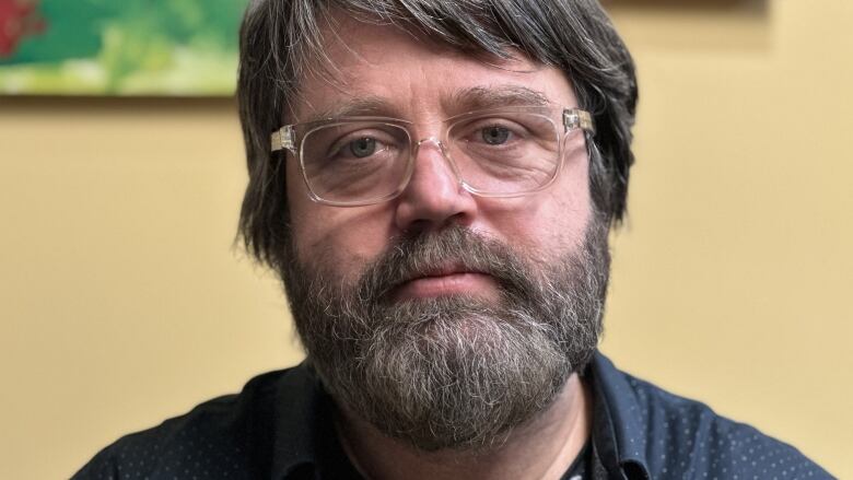 A man with glasses and a beard, in close up.