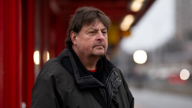 A man at an outdoor bus station.