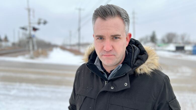 A man stands outside with a jacket.