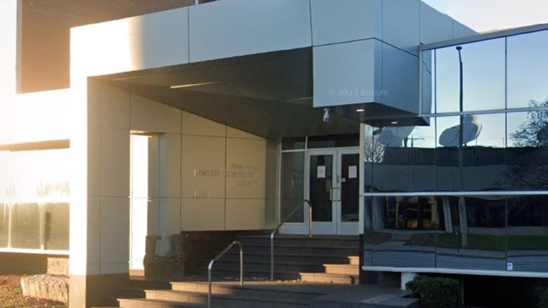 The entrance to an official building with steel architecture and glass windows.