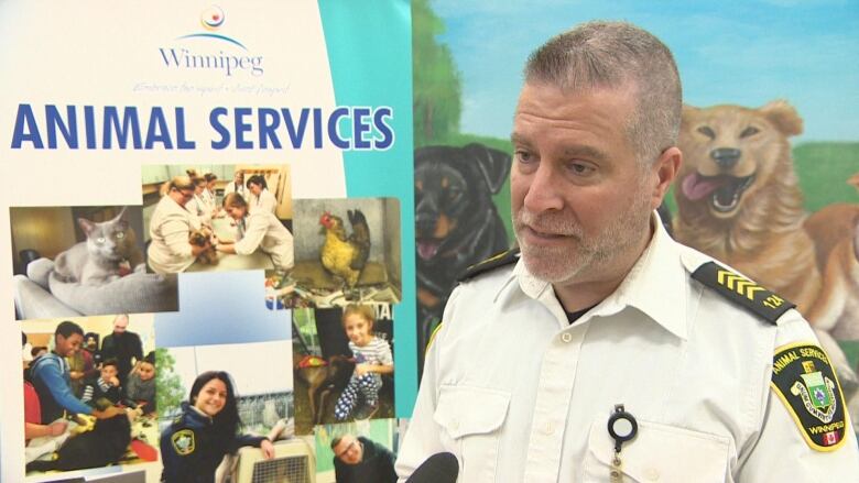 A man in a white uniform stands in front of a sign that says Animal Services.