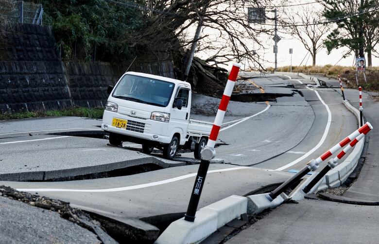 A vehicle drives along a quake-damaged road in Wajima, Japan.