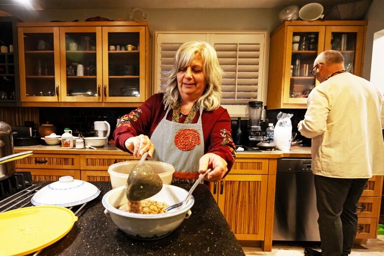 A woman mixes ingredients in a bowl on a kitchen counter.