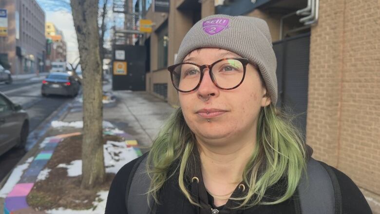 a person with green hair is seen wearing a union touque and tortoiseshell glasses.