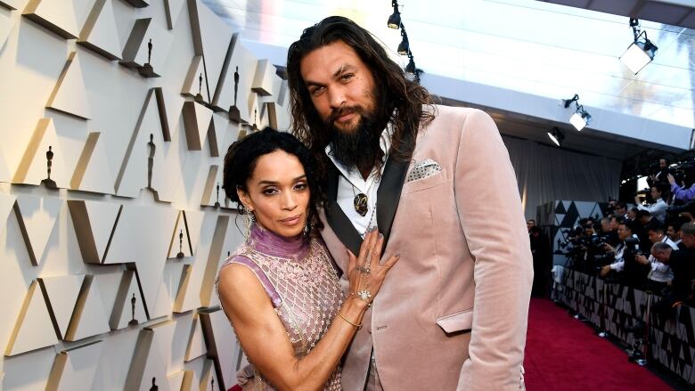 Two people embrace while posing for a photograph on a red carpet.