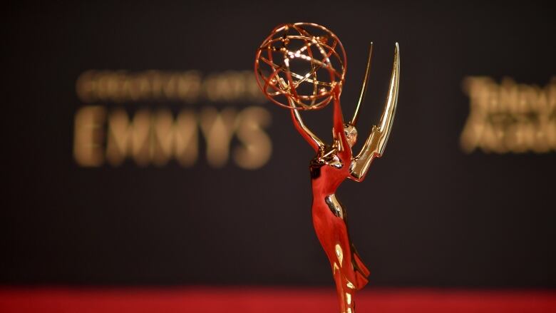 A golden statuette of a person holding up a sphere is displayed on a tabletop.