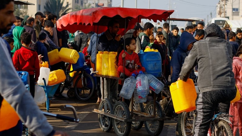 Palestinians with empty water bottles wait to fill them in Rafah. 