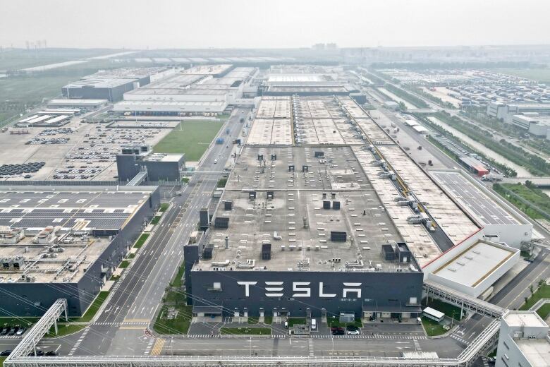 An aerial view of a large building with a huge sign reading 'Tesla.'