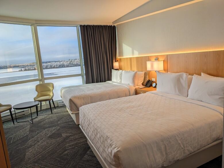 shot of hotel room capturing two beds and the view of the lake outside the window.