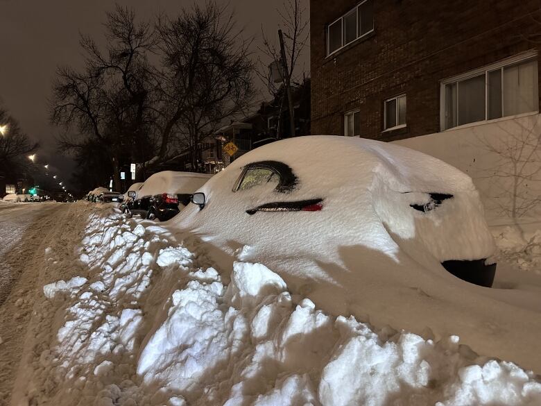 A car almost completely covered in heavy snow. 