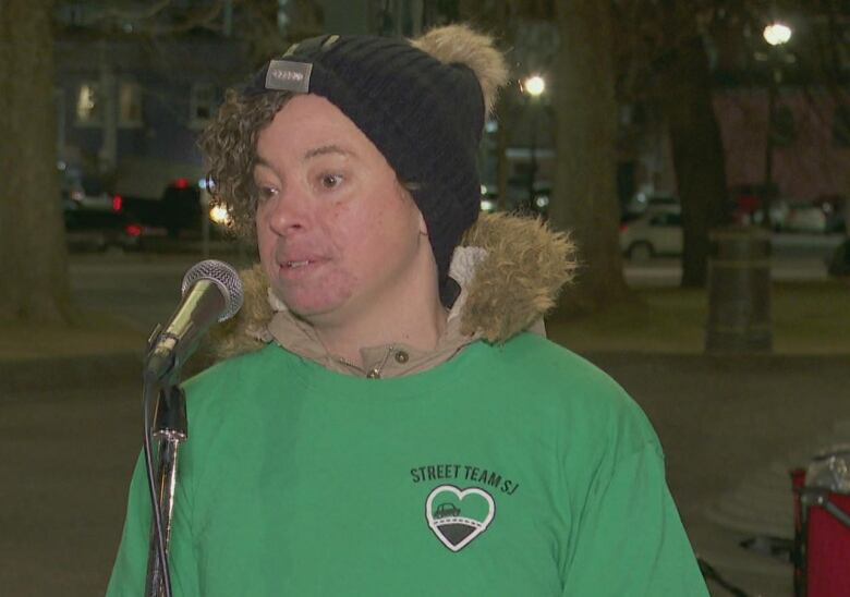 Woman standing in front of mic, speaking. 