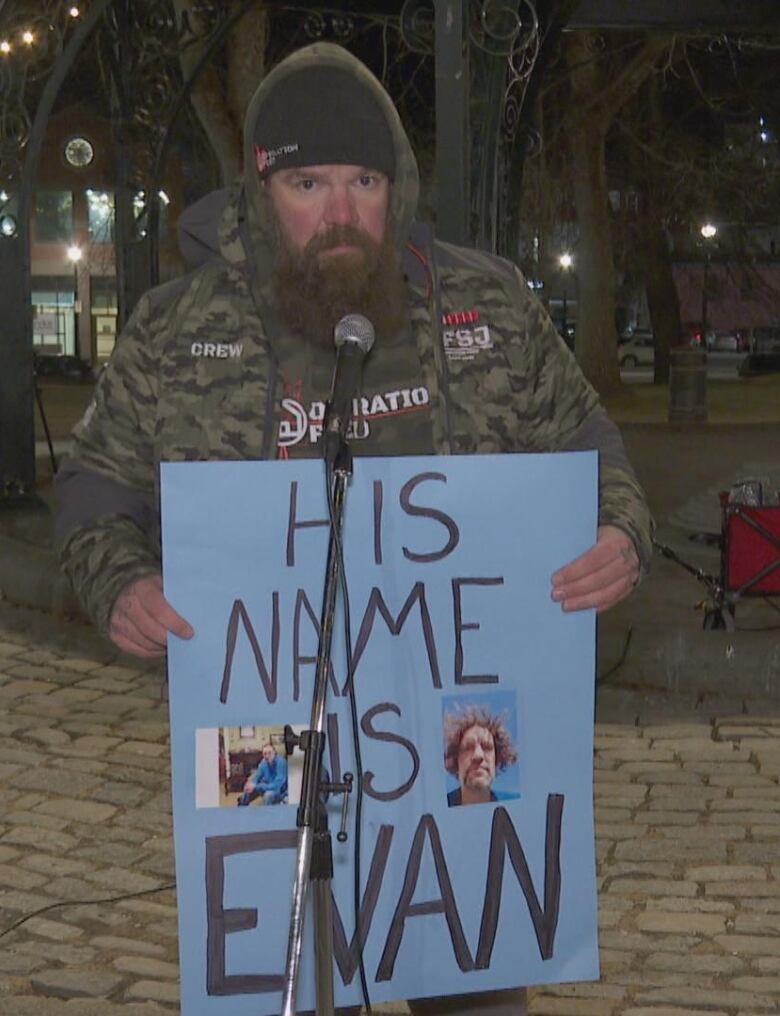 Man standing in front of mic holding a sign saying 