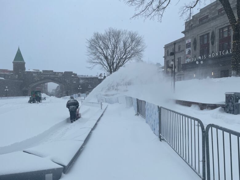 A man uses a snowblower in an area blanketed with snow. 