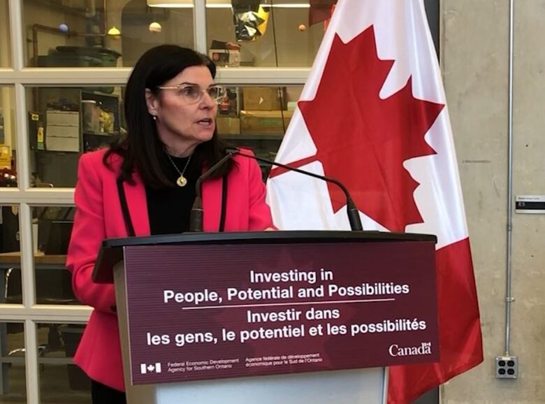 Woman standing at podium with Canadian flag behind her