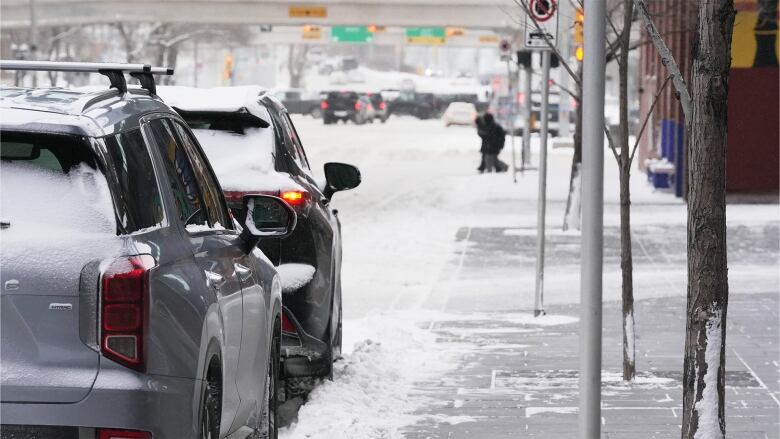 Cars parked on the side of a snowy road.