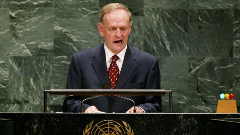 A man speaks at a podium with the UN logo.