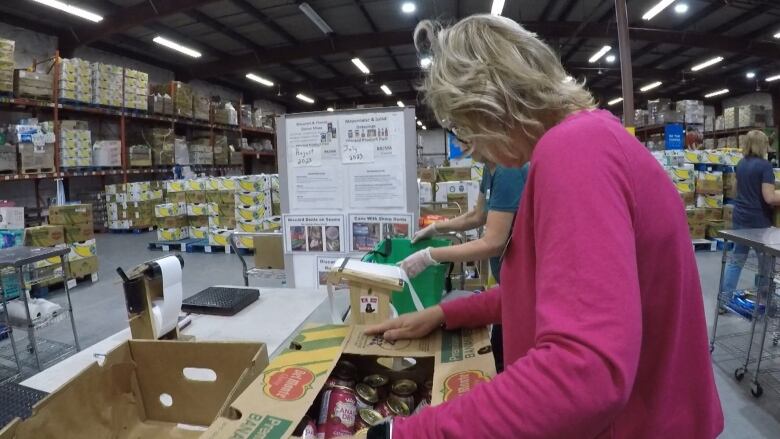 A woman packs food in a box at a food bank