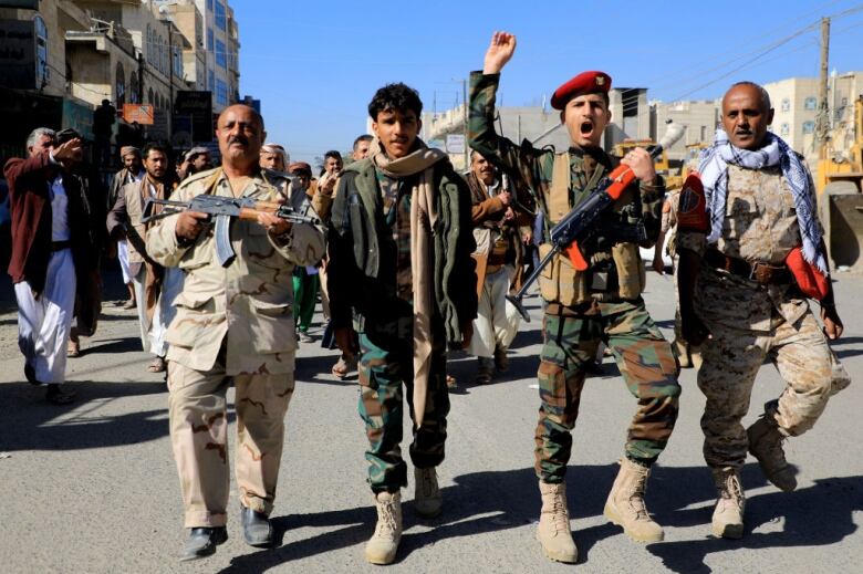 Houthi fighters brandish their weapons during a march.