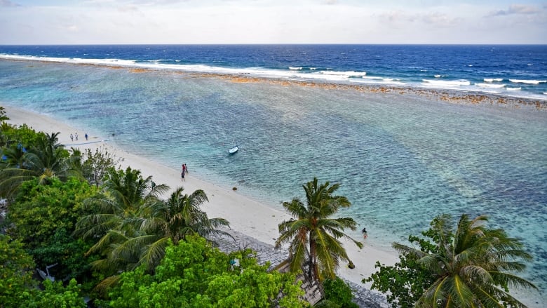 People enjoying a walk on the beach in Hulhumale, on the small island nation in the Indian Ocean, on December 26, 2023. 