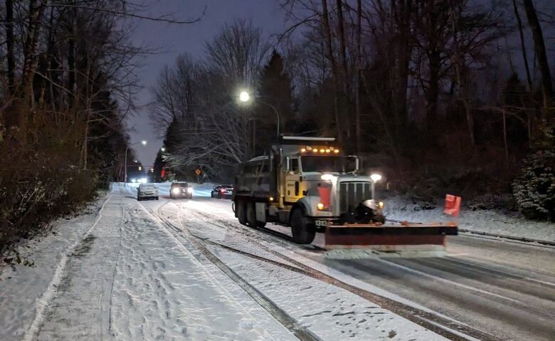 A snow plow clears and salts Forest Grove Drive in Burnaby, B.C., during a winter storm on Jan. 11, 2024.