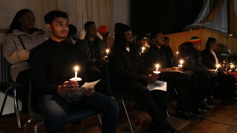 People hold candles while attending a vigil. 