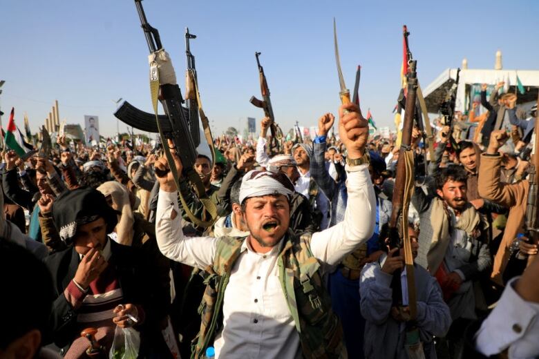 Men hold weapons in the air during a protest.