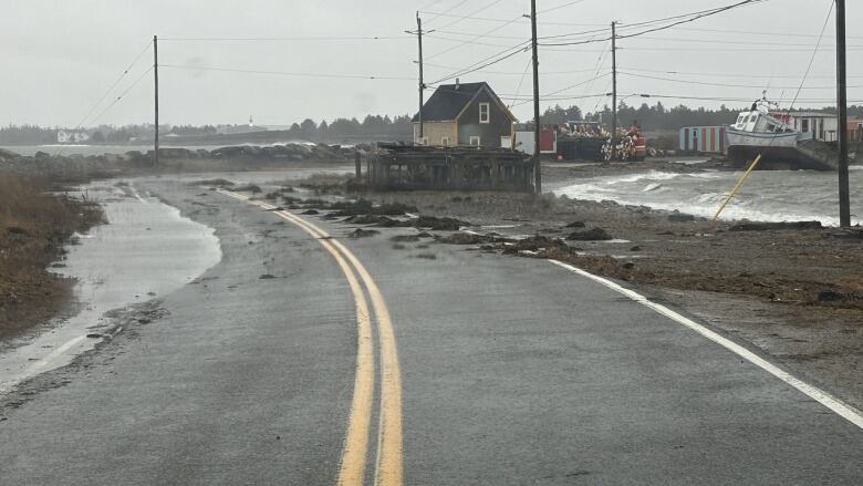 there is sea weed on a road surrounded by water. The waves are rough and a boat is rocking. 