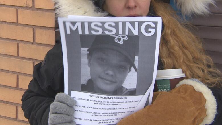 A person holds up a missing poster