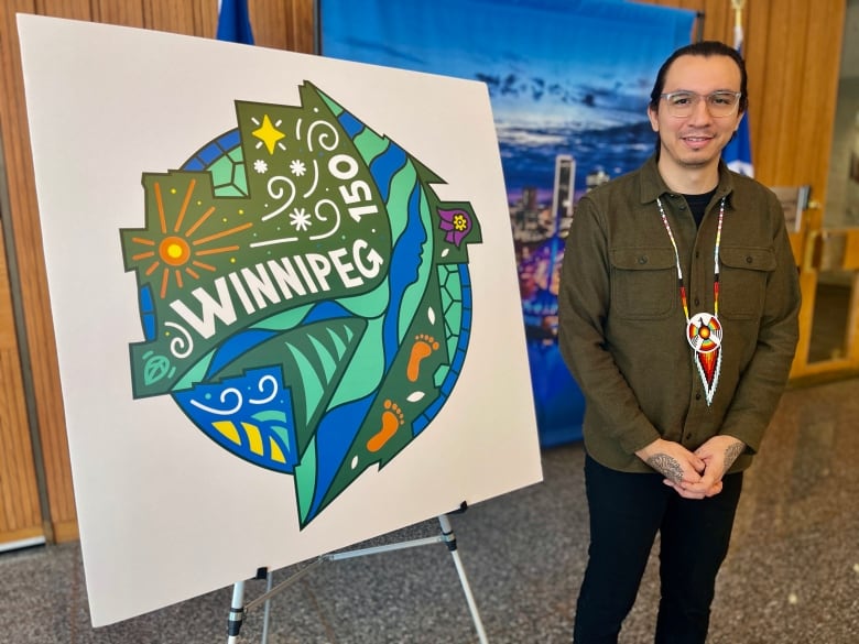 A man stands by an easel with the Winnipeg 150 logo.