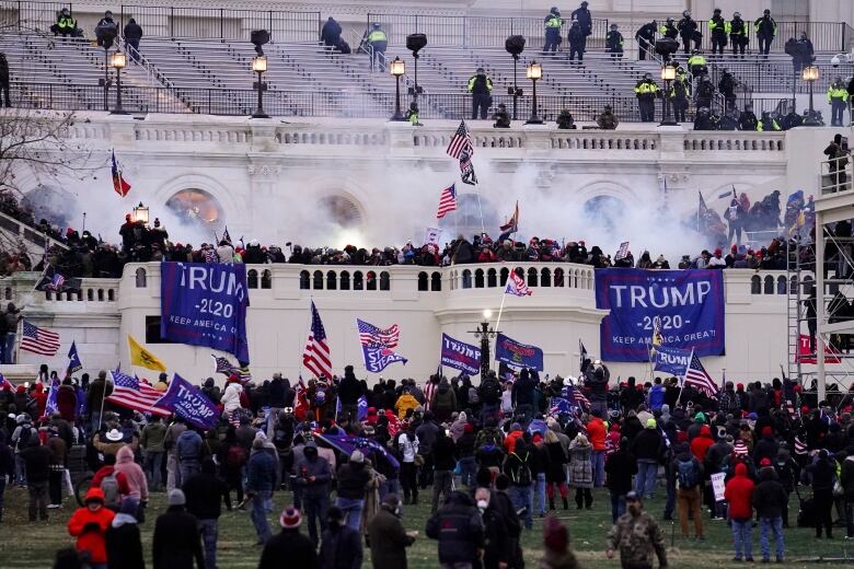 Smoke and Trump signs abound in a crowd around the US Capitol