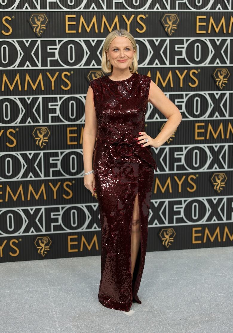 A woman wears a sparkly, wine-coloured dress.