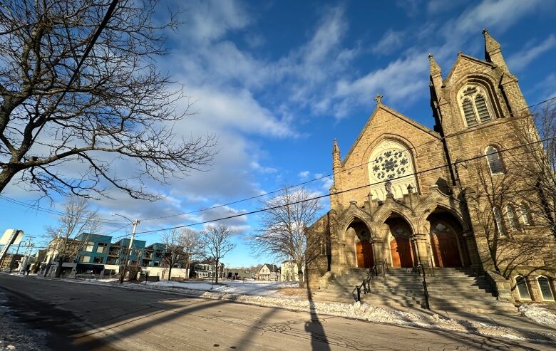 A wide-angle image of a large stone church entrance with snow on the ground. 