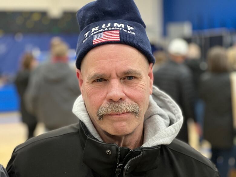 Man with mustache and toque that says Trump.