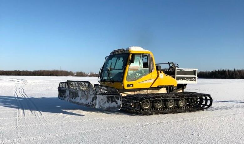 A big yellow snow machine is seen on a sunny day.