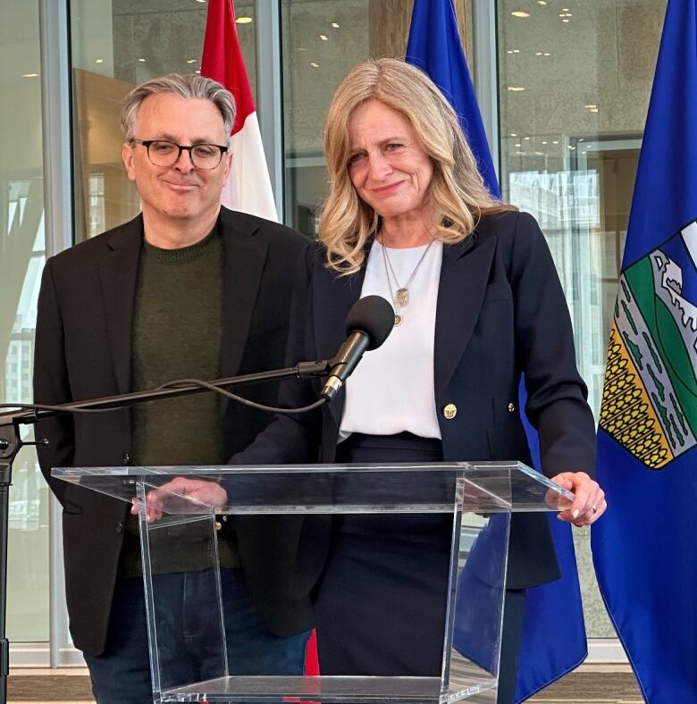 A woman and a man stand behind a podium.