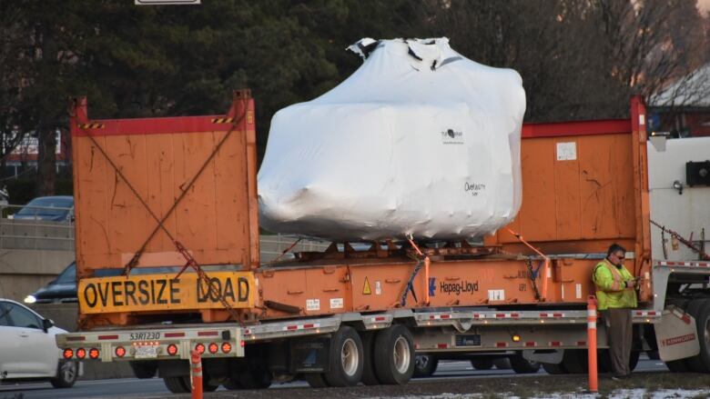 helicopter in shrinkwrap sits on the back of a flatbed truck