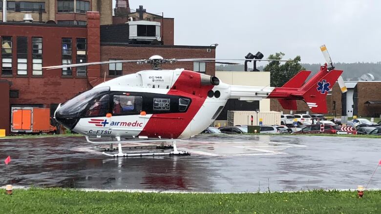 A helicopter sits on a helipad in the rain.