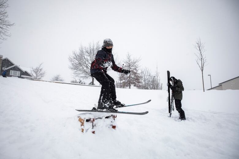 A young boy poses in skis on top of a pile of snow.