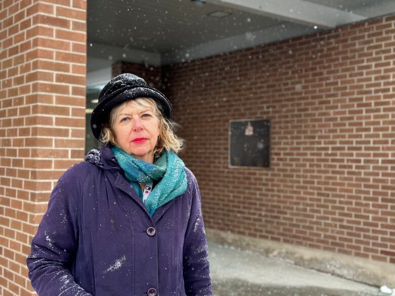 Woman in hat stands in front of building