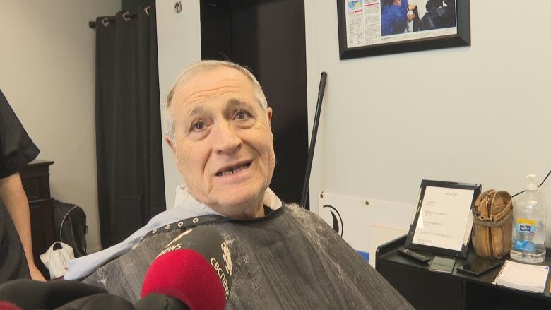 A man in a barbershop being interviewed.