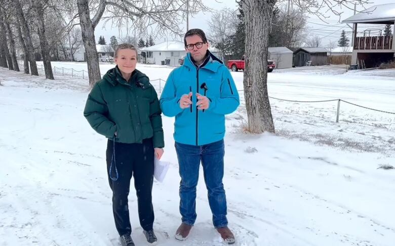 A woman and man stand in the snow.