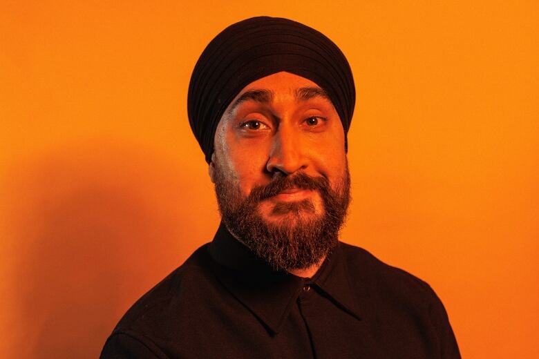 A man lit by orange lighting is photographed in close-up.