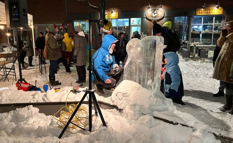 Two people stand around a block of ice.