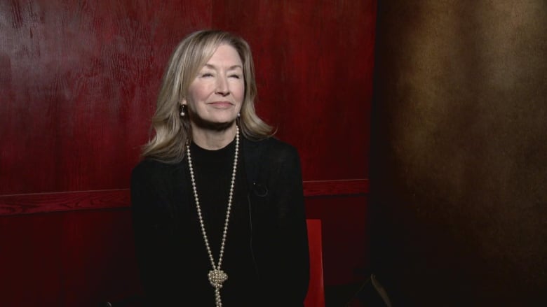 A woman sitting against a red wall.