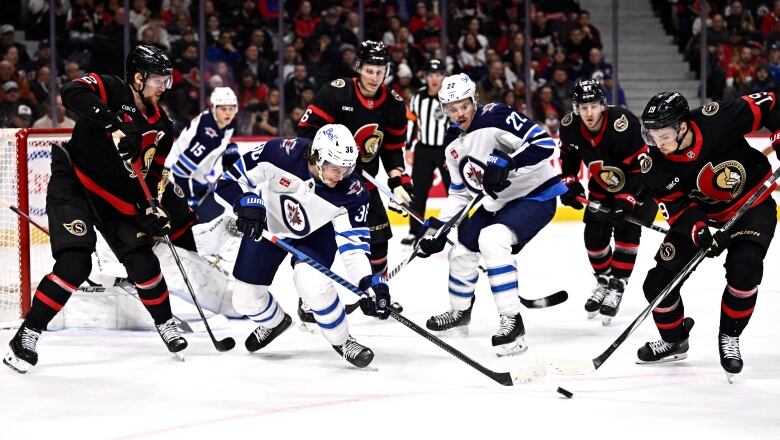 Hockey players battle for a loose puck.