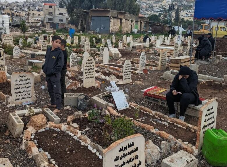 People gather around burial plots.