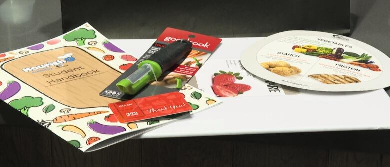 a book, a vegetable peeler and a gift card placed on a table.