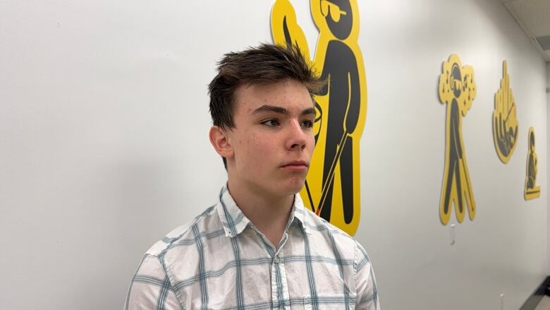 A teenage boy stands in a brightly lit room.