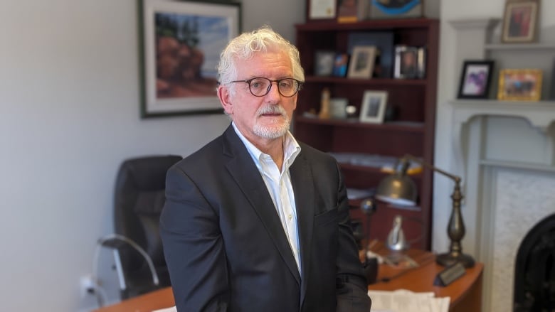 Man with grey hair sitting in office.